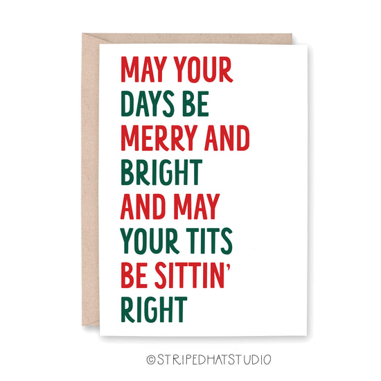 A white greeting card with a kraft envelope behind it, featuring the phrase 'MAY YOUR DAYS BE MERRY AND BRIGHT AND MAY YOUR Tits BE SITTIN' RIGHT' in alternating red and dark green block letters. The card is shown on a white background with a small copyright watermark at the bottom.